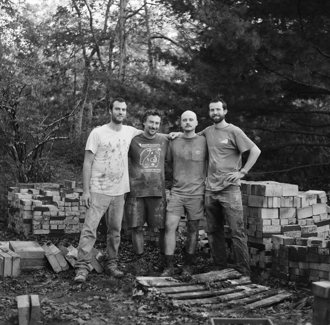 group of men in front of a stone kiln construction